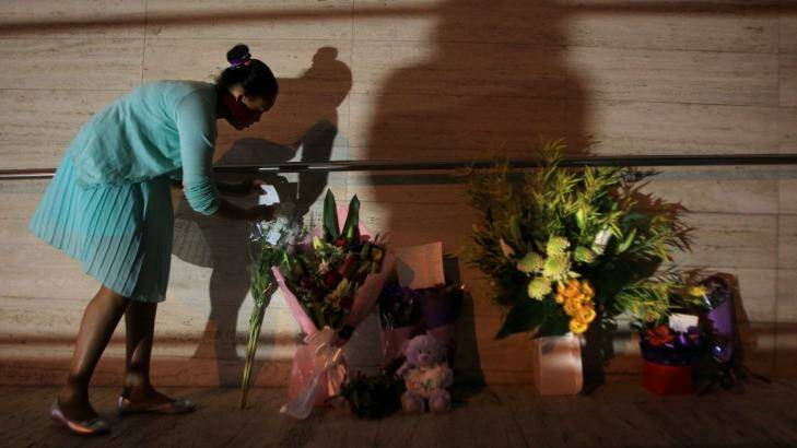 A young girl leaves flowers at the front of NSW Police Headquaters in memory of police employee Curtis Cheng. Photo: James Alcock