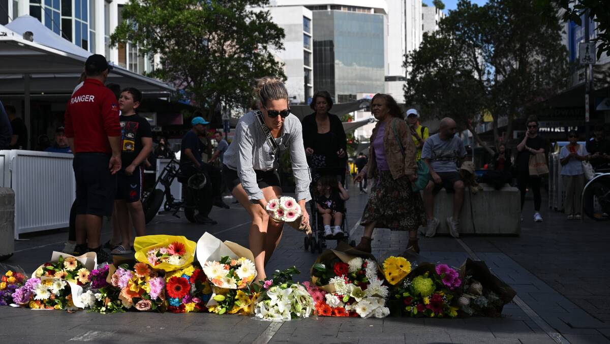 Local residents begin to lay flowers at the scene of yesterday's mass stabbing at Bondi Junction, Sydney, Sunday, April 14, 2024. (AAP Image/Dean Lewins)