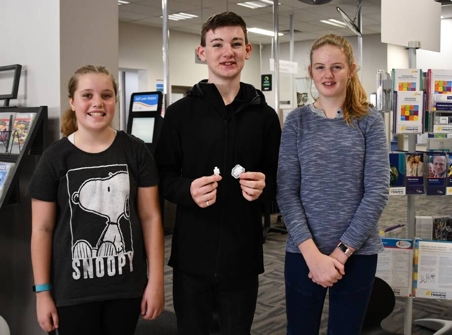 Rachael Honeywill, 13, Hayden Honeywill, 17, and Lily Rosetta, 12. Hayden is holding the two robots made by the 3D printer at Culcairn Library.