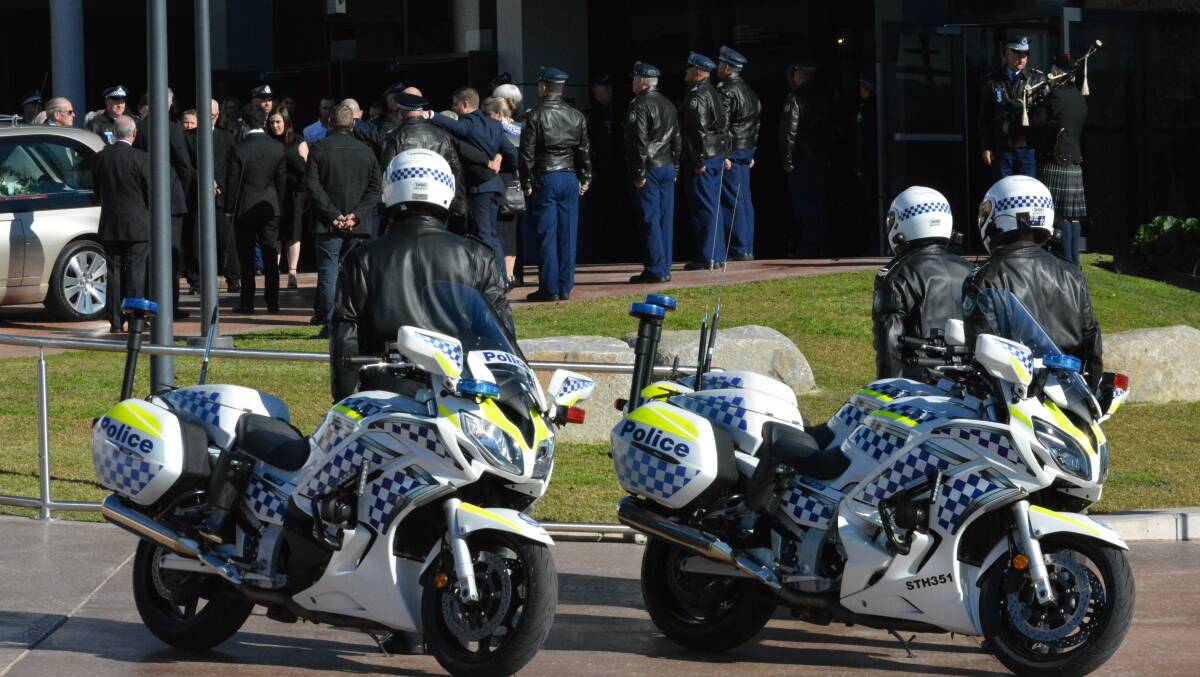 The thin blue line: Motorcycle officers watch on their colleagues form a guard of honour between the civic centre and hearse.