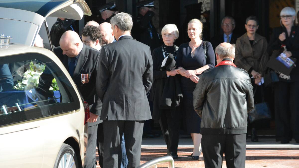 Comforting hand: Mick Horne's widow Mel (right) watches as her husband's coffin is put into a hearse.