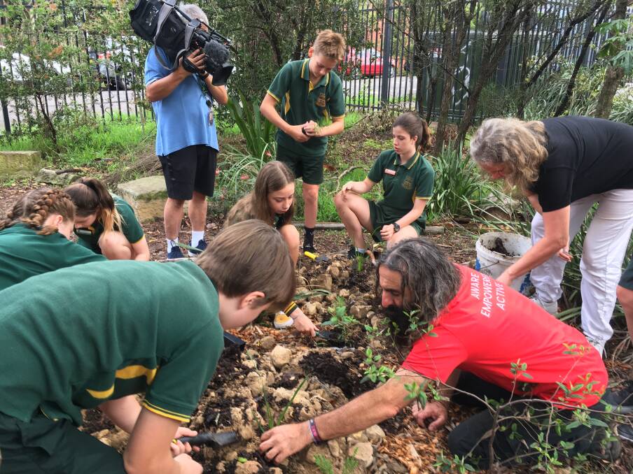 PLANTING IDEAS: Celebrity gardener Costa Georgiadis encourages Camdenville Public School students to see what goes on a ground level when planting fire retardant native shrubs.