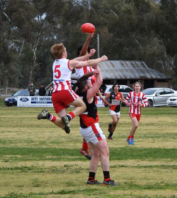 UP THERE: Henty's Jimmy Ellis and William Farrer  leap over Howlong's Beau Packer. Picture: Lorri Roden