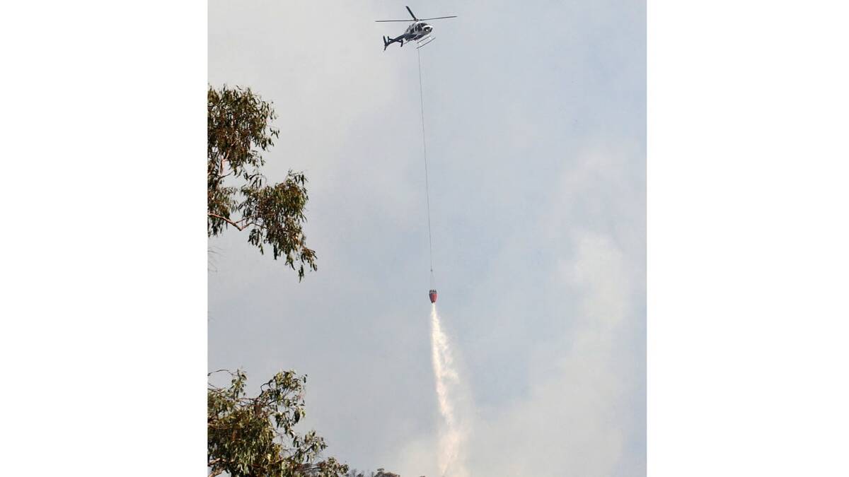 A helicopter drops water on a hard to reach section of the fire.  Photo: Ben Eyles